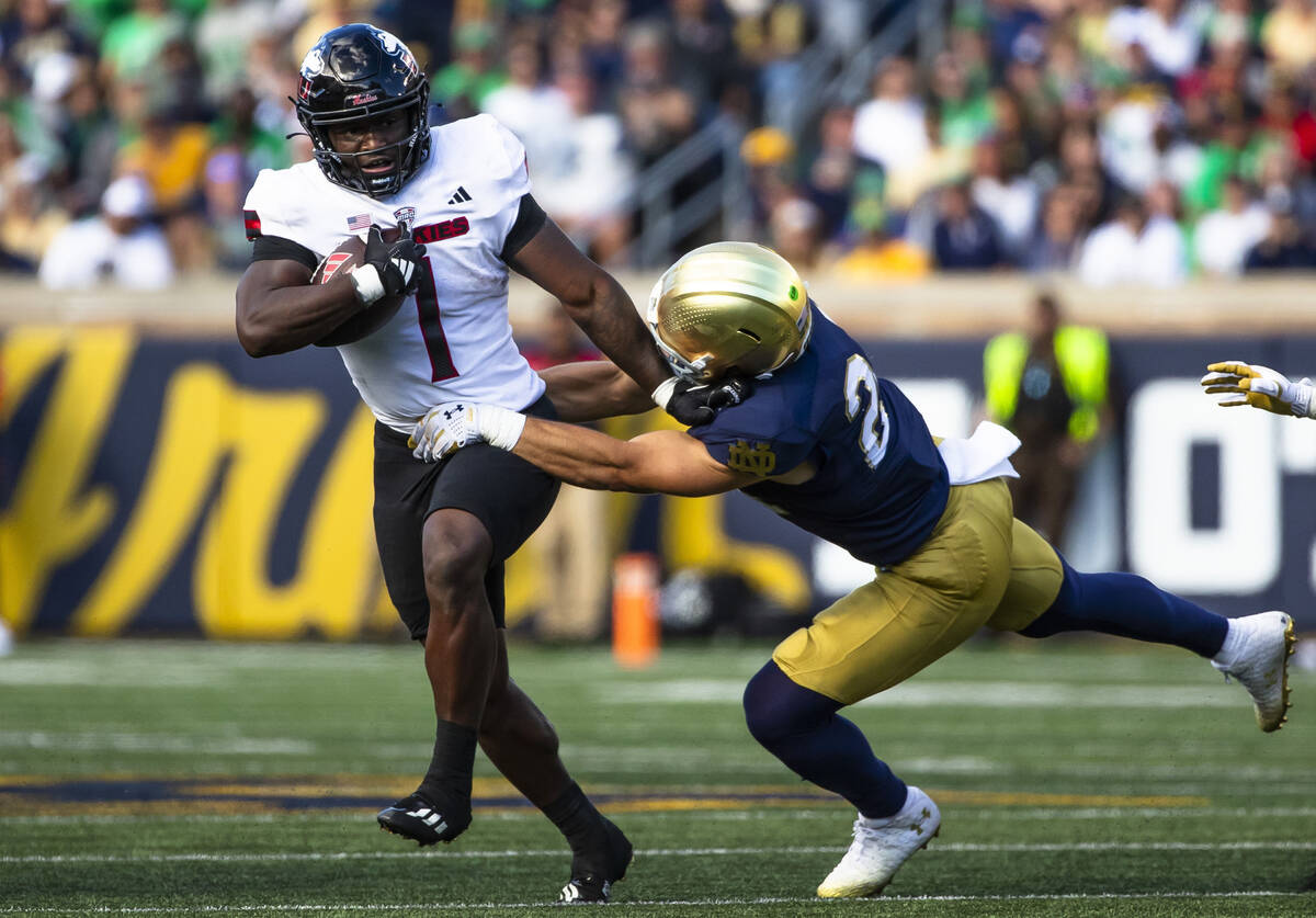 Northern Illinois running back Antario Brown (1) tries to get past Notre Dame running back Jada ...