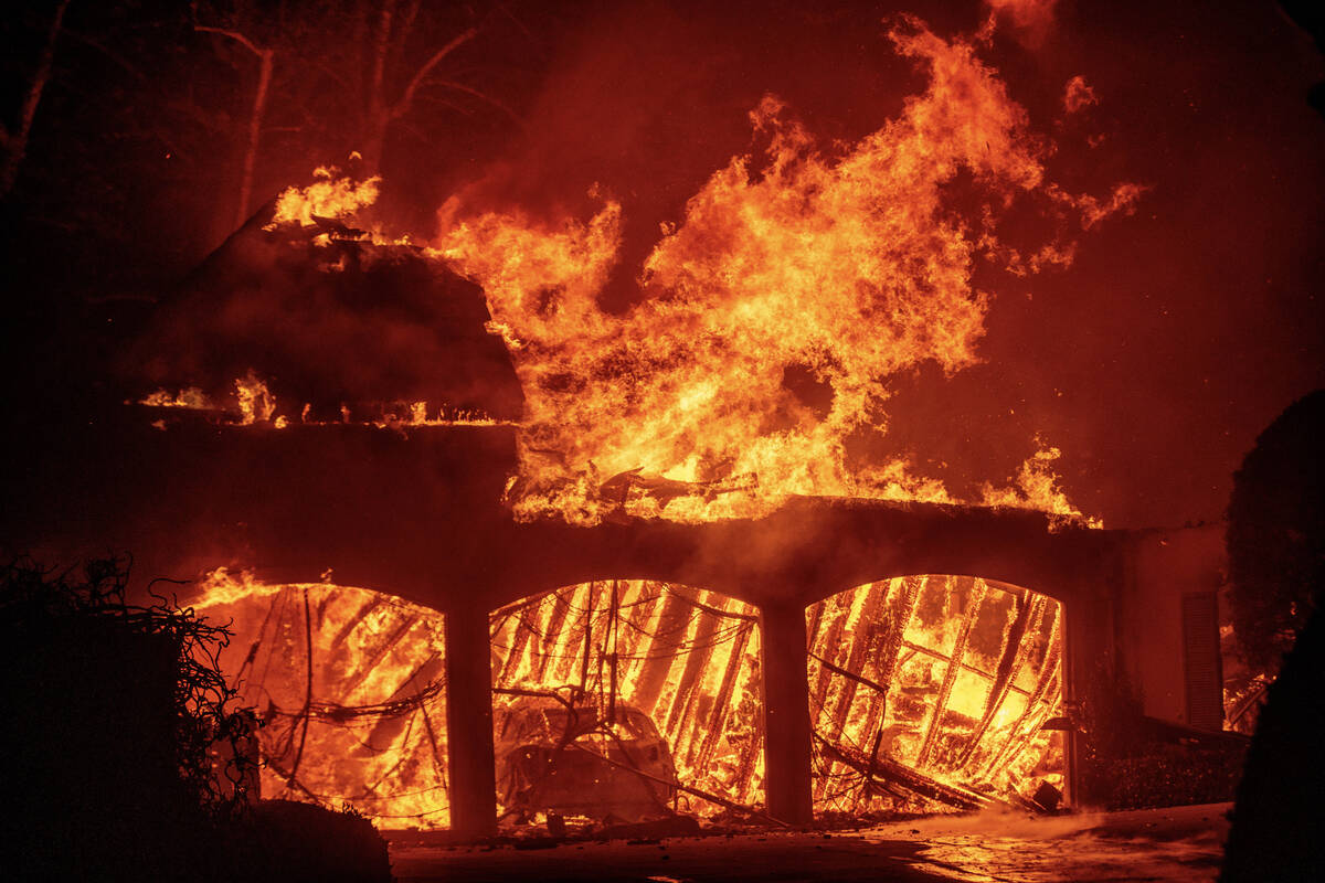 The Eaton Fire burns a residence Wednesday, Jan. 8, 2025 in Altadena, Calif. (AP Photo/Ethan Swope)