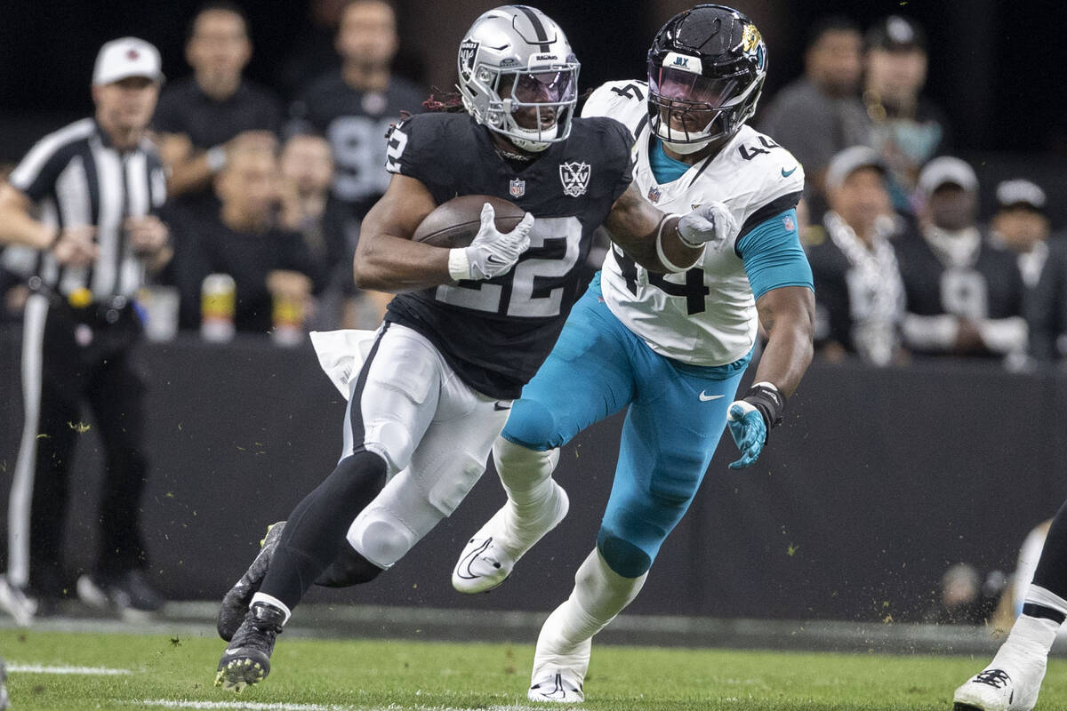 Raiders running back Alexander Mattison (22) rushes past Jacksonville Jaguars defensive end Tra ...