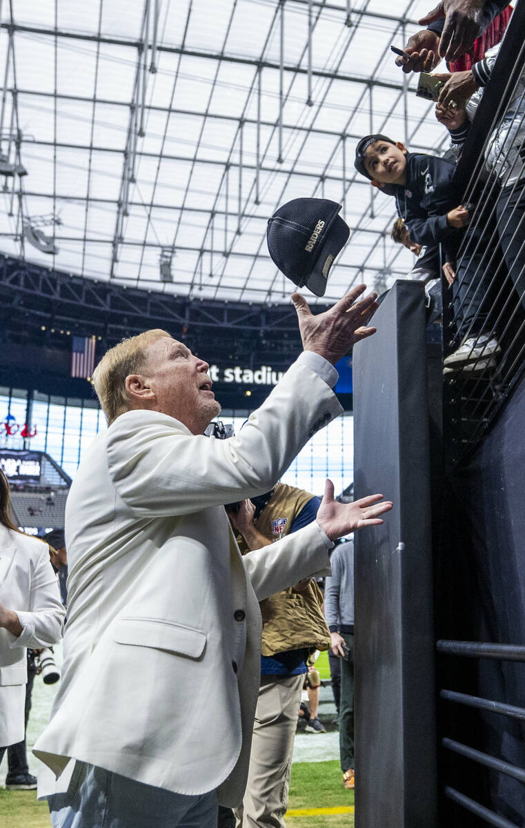 Raiders owner Mark Davis chats catches a hat to sign for a fan in the tunnel during warm ups be ...