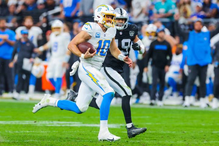 Los Angeles Chargers quarterback Justin Herbert (10) scrambles as Raiders defensive end Charles ...