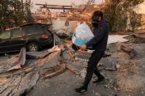 Josh Lederer wears a mask to protect him from fumes as he retrieves his children's clothes from ...