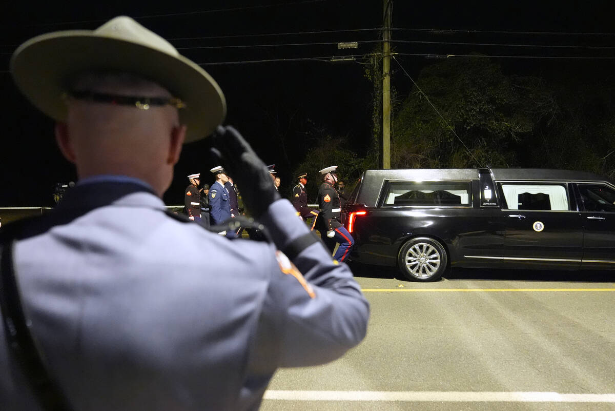 A member of the Georgia State Patrol salutes as the hearse carrying former President Jimmy Cart ...