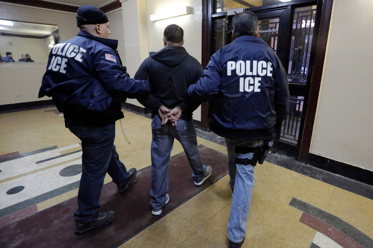 Immigration and Customs Enforcement officers escort an arrestee in an apartment building in the ...