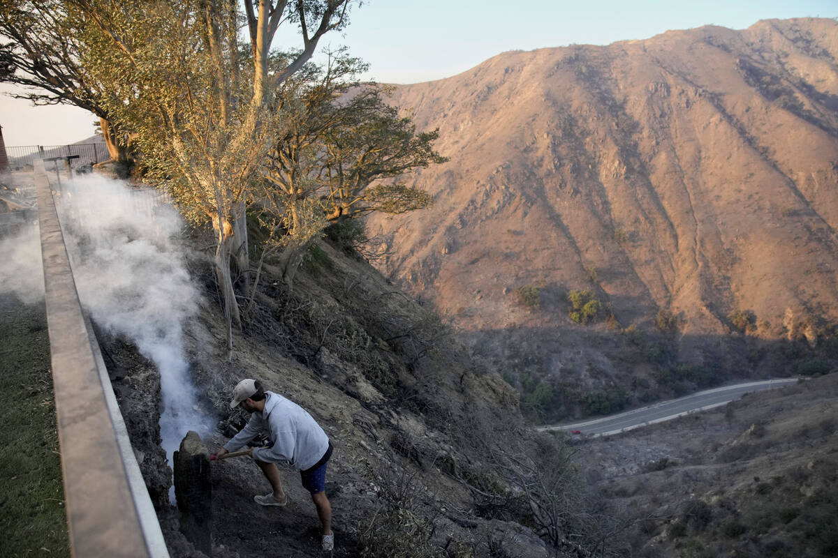 Garrett Yost gathers puts out hotspots from his neighbors' fire-ravaged properties in the after ...