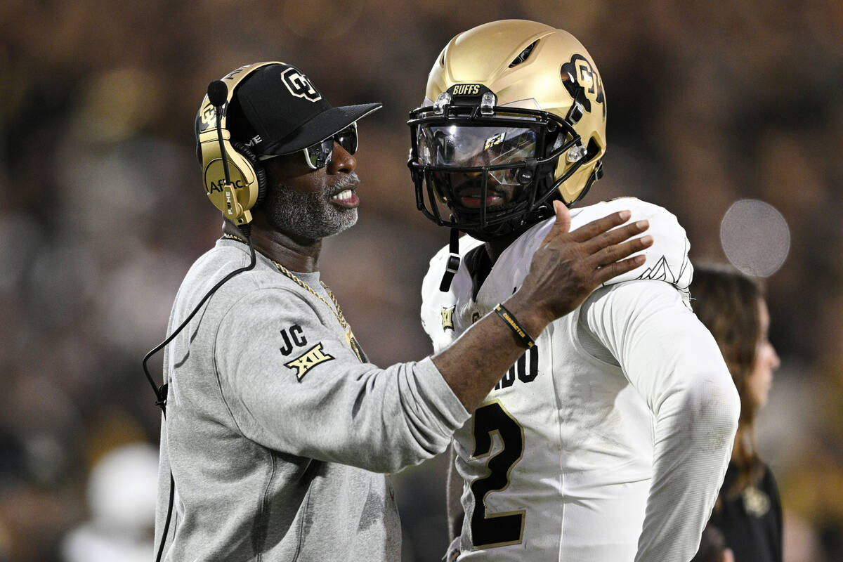 FILE - Colorado head coach Deion Sanders, left, talks with quarterback Shedeur Sanders (2) duri ...