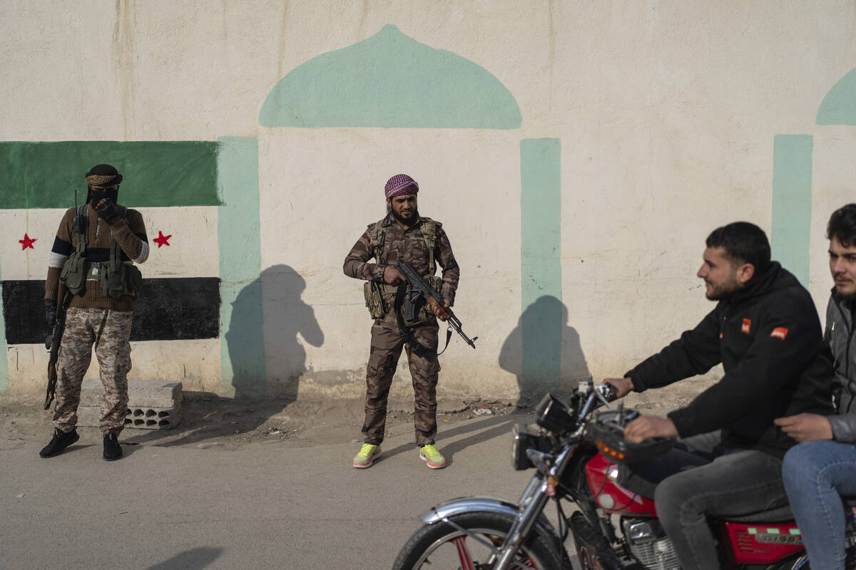 Security members of the new Syrian government stand guard outside the shrine of Sayyida Zaynab, ...