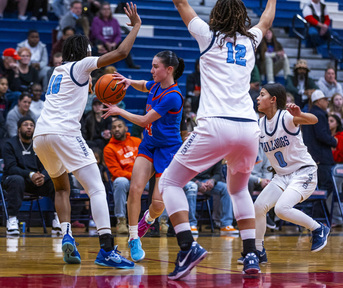 Bishop Gorman guard Kenzee Holton (14) passes while covered all around by Centennial guard Sana ...