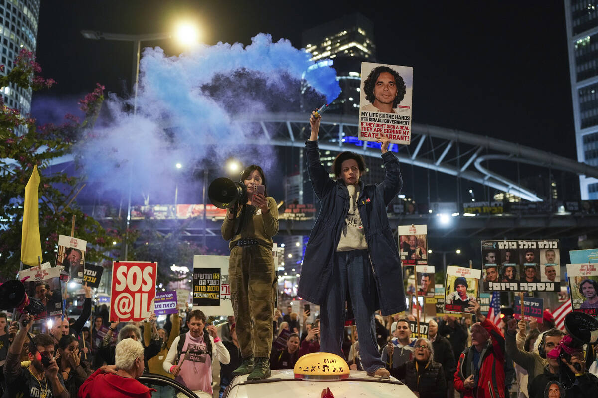 Demonstrators hold signs and flares during a protest calling for the immediate release of the h ...