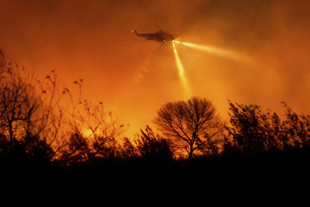 A helicopter drops water while fighting the Auto Fire in Ventura County, Calif., on Monday, Jan ...