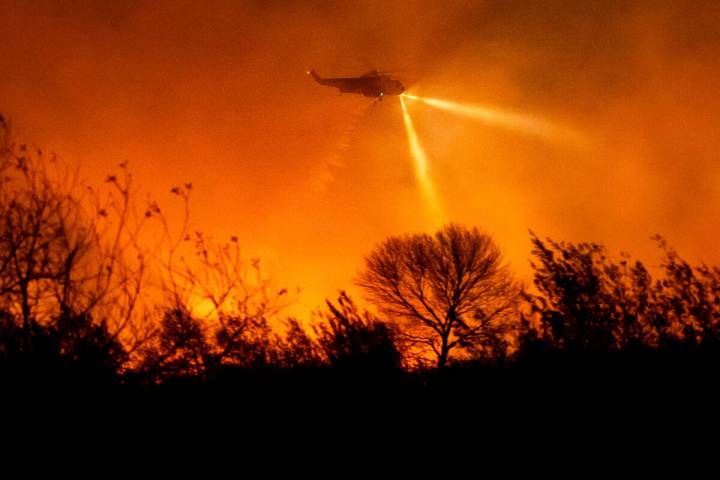 A helicopter drops water while fighting the Auto Fire in Ventura County, Calif., on Monday, Jan ...