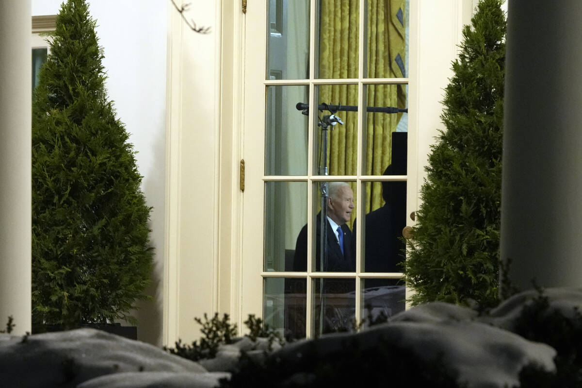 As seen through a window from the Colonnade outside the Oval Office, President Joe Biden speaks ...