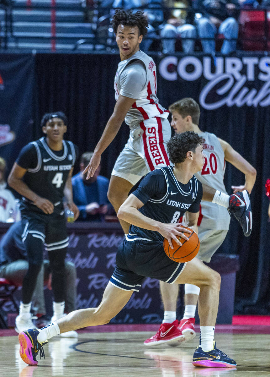 UNLV guard Dedan Thomas Jr. (11) leaps past Utah State Aggies guard Drake Allen (8) while defen ...