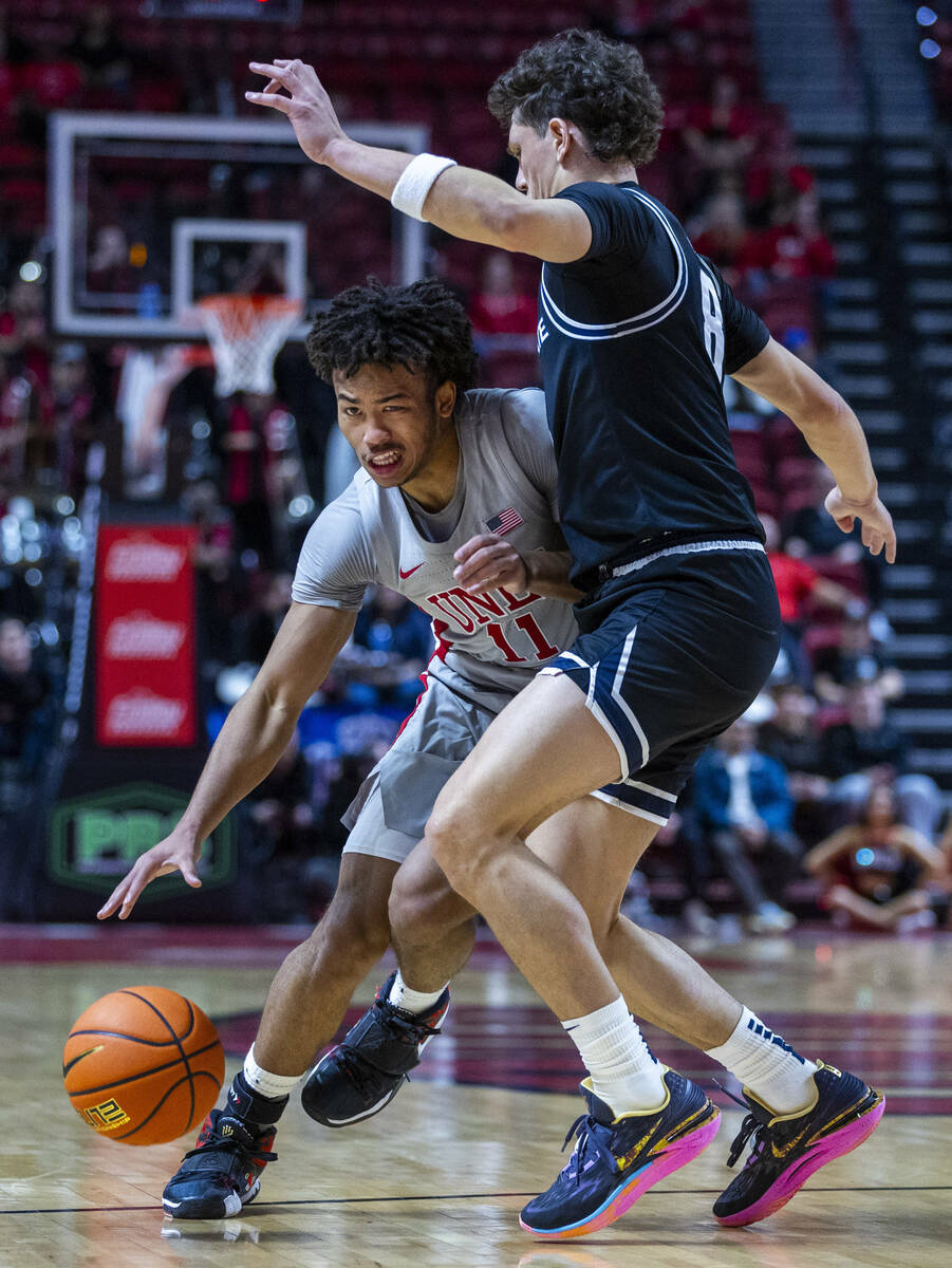 UNLV guard Dedan Thomas Jr. (11) drives the lane against Utah State Aggies guard Drake Allen (8 ...