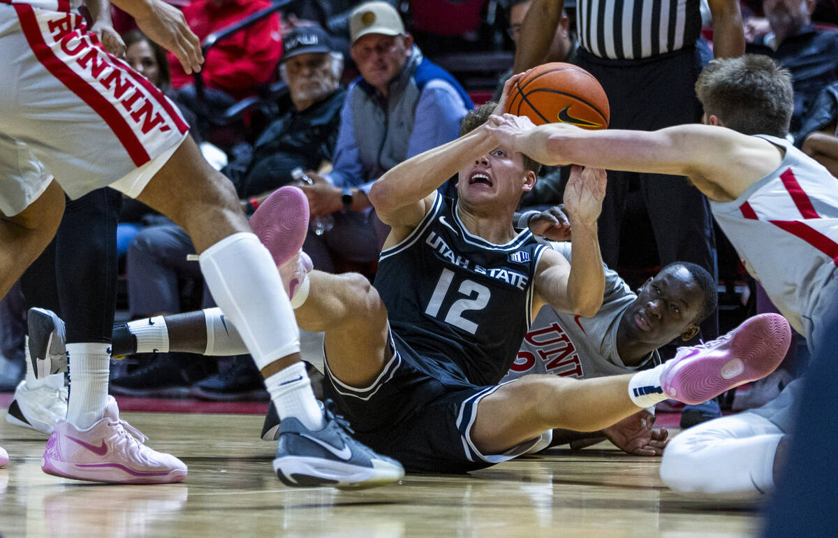 Utah State Aggies guard Mason Falslev (12) looks to pass from the court with UNLV forward Pape ...