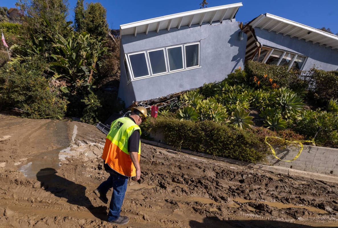 A DWP worker inspects a home that survived the Palisades fire only to be destroyed in a landsli ...