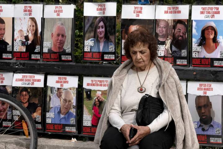 A woman pauses near posters of hostages held by Hamas in the Gaza Strip, in Tel Aviv, Israel, a ...