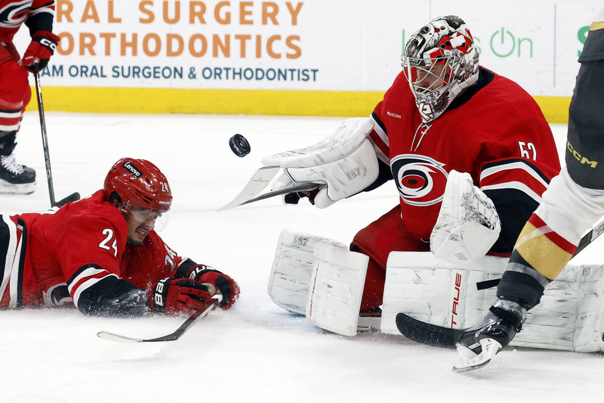 Carolina Hurricanes goaltender Pyotr Kochetkov (52) paddles the puck away in front of a sliding ...