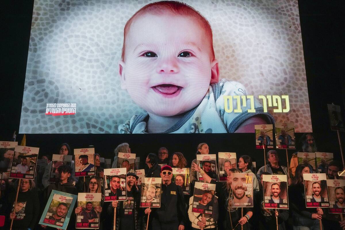 Demonstrators hold portraits of hostages held by Hamas in the Gaza Strip as a video featuring K ...