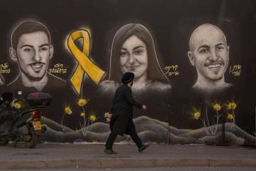 FILE - An Ultra-orthodox Jewish man walks past graffiti portraits of hostages held by Hamas in ...