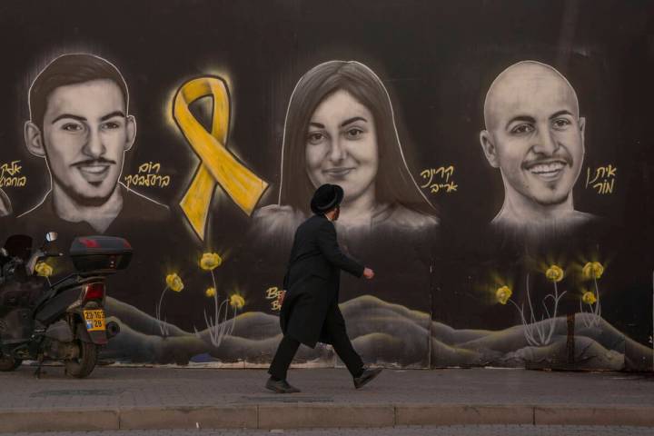 FILE - An Ultra-orthodox Jewish man walks past graffiti portraits of hostages held by Hamas in ...