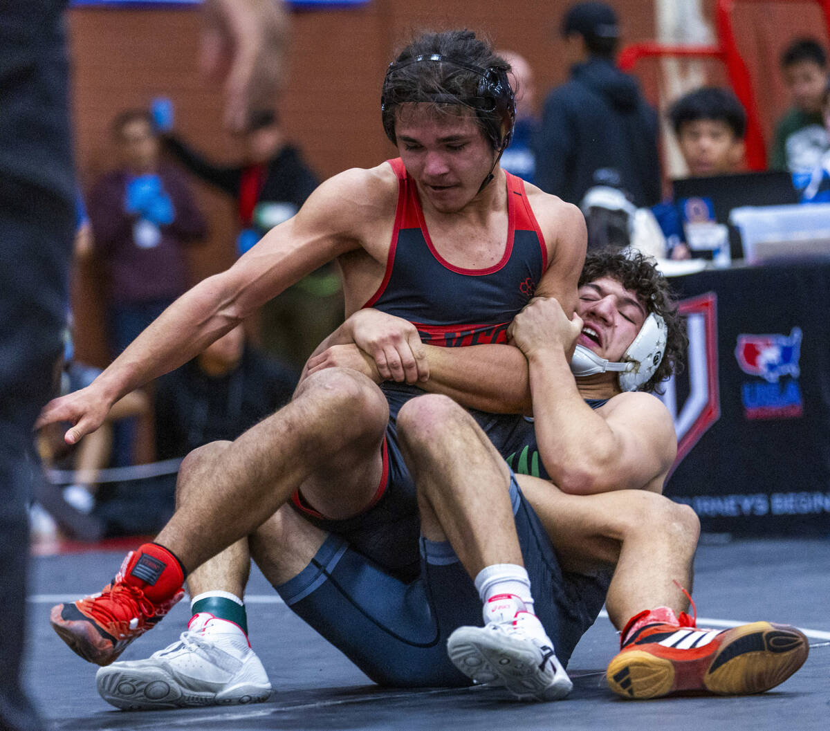 Las Vegas High's Leonard Castellanos is wrapped up from behind by SLAM's Gabriel Delgado during ...