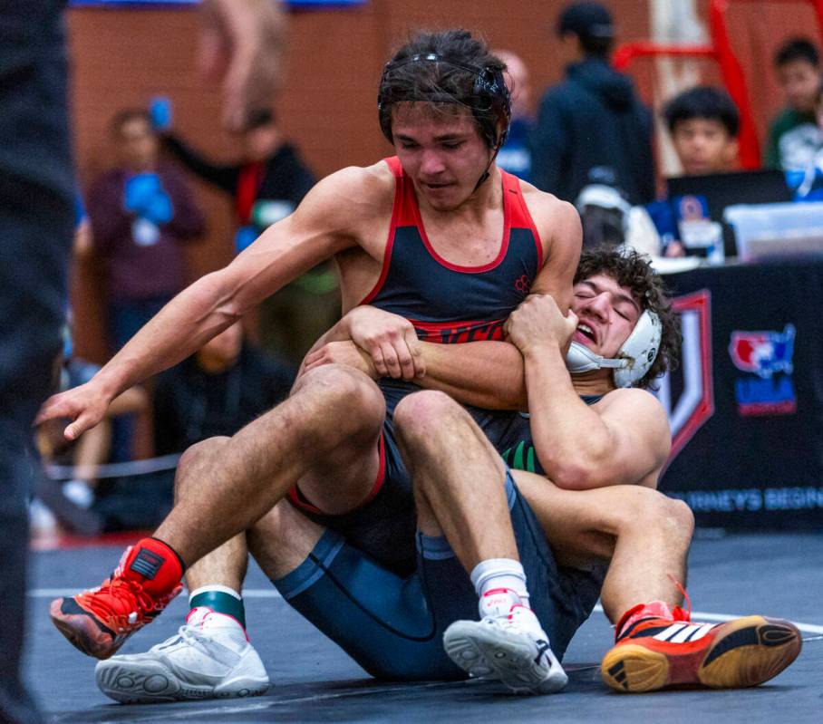 Las Vegas High's Leonard Castellanos is wrapped up from behind by SLAM's Gabriel Delgado during ...