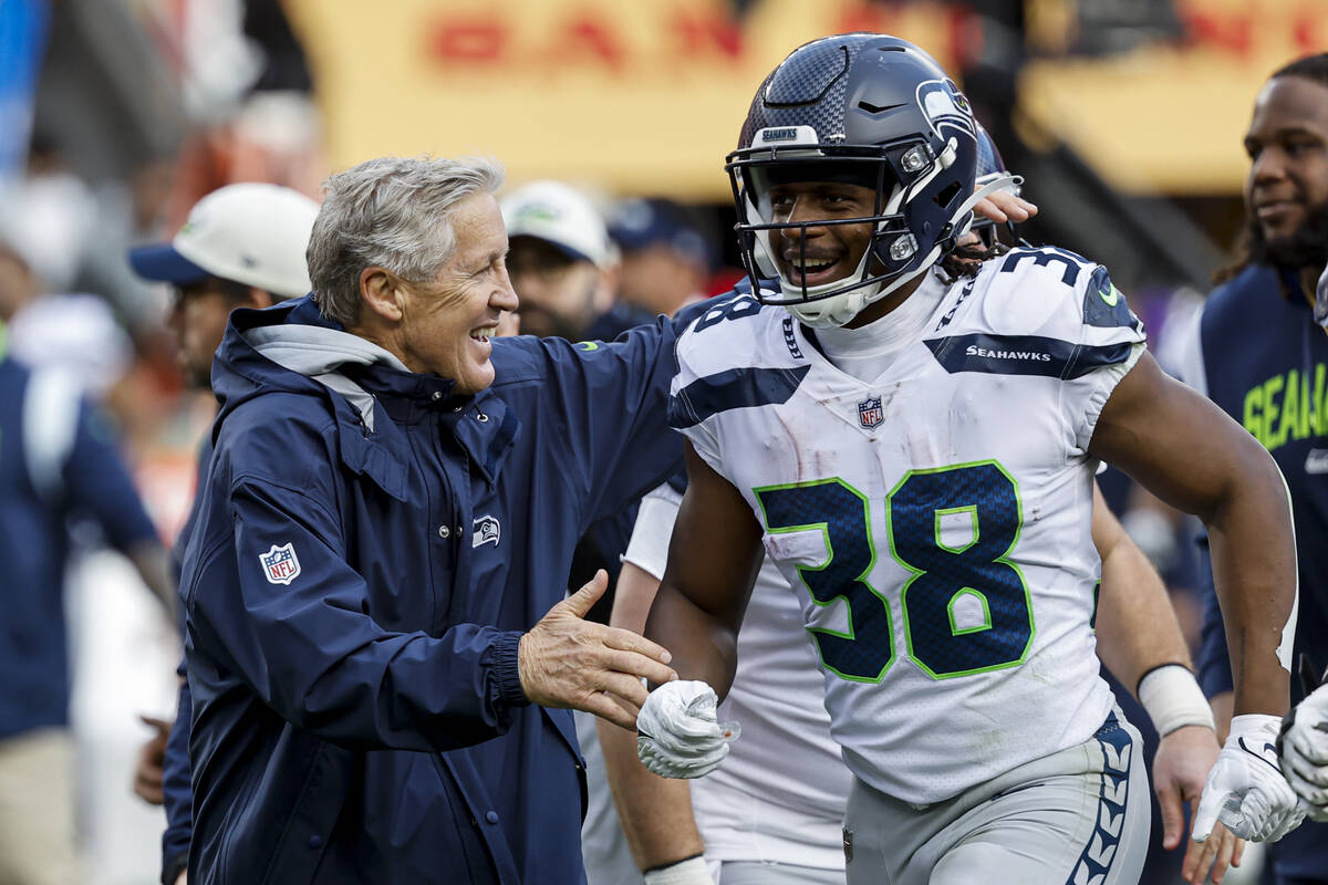 Seattle Seahawks head coach Pete Carroll, left, and Godwin Igwebuike (38) celebrate after place ...