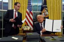 President Donald Trump holds up an executive order commuting sentences for people convicted of ...