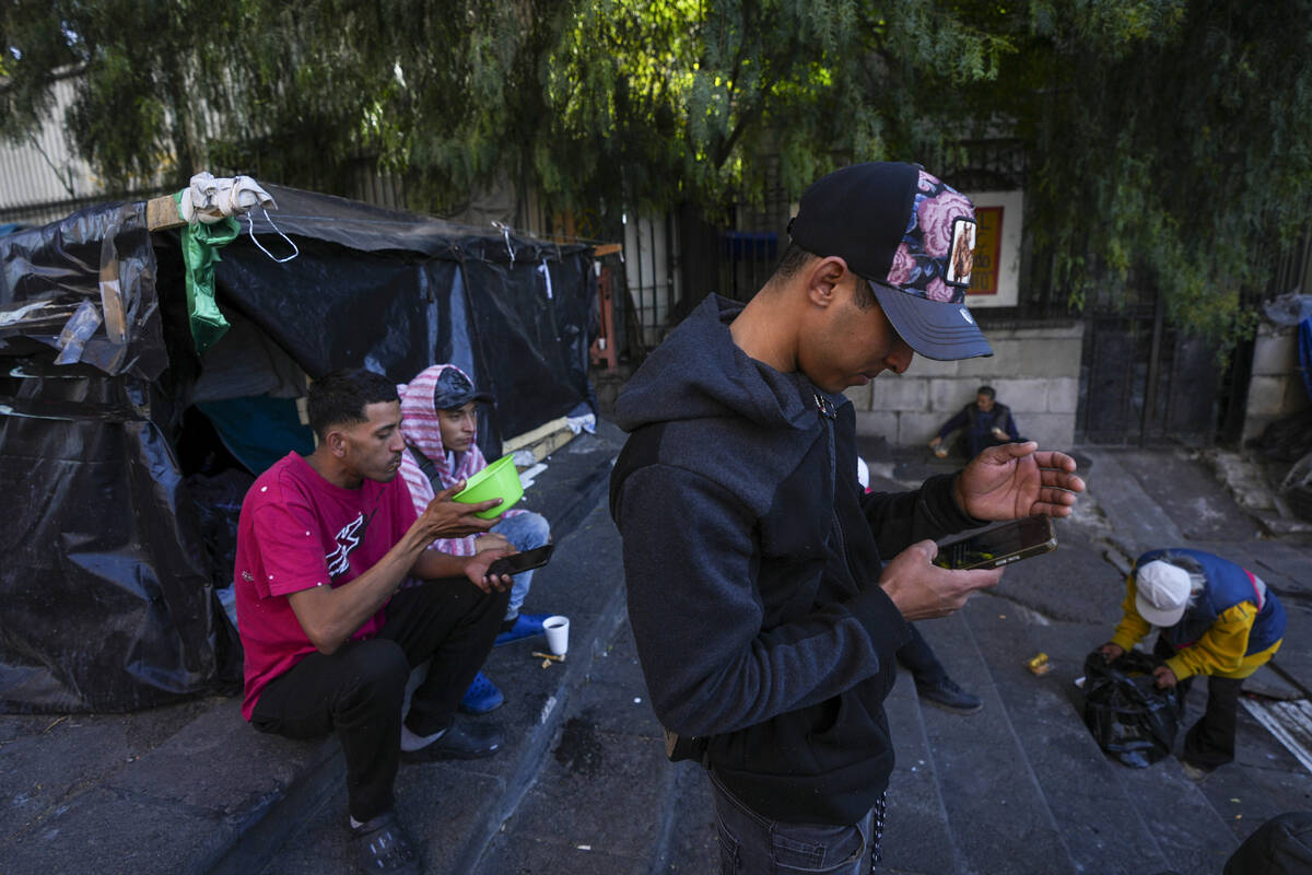 Yender Romero, from Venezuela, uses his cell phone to listen to news on the inauguration of U.S ...