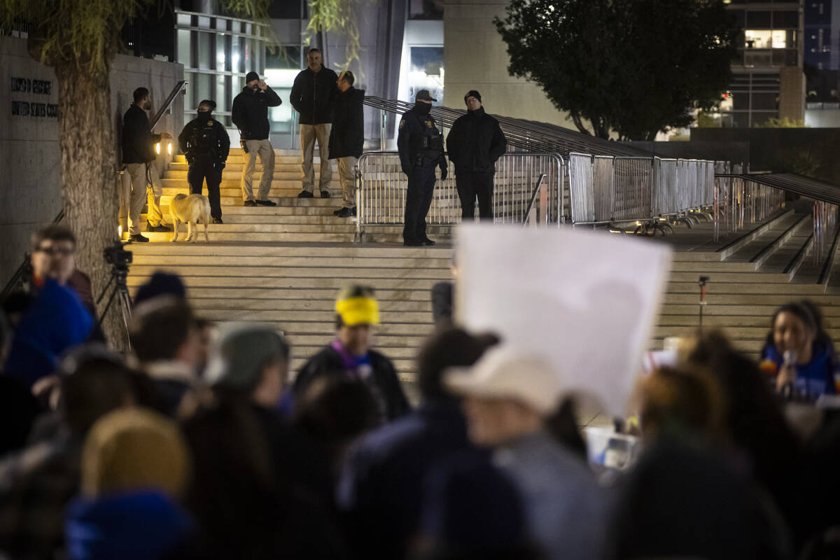 Federal agents stand outside of the Lloyd George U.S. Courthouse as people participate in a ral ...