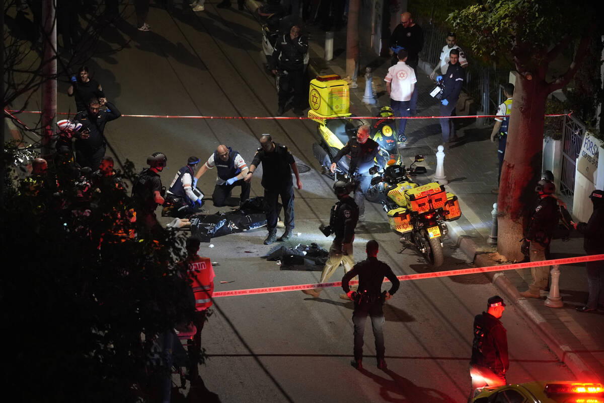 Israeli police check the body of a suspected attacker at the scene of a stabbing attack, where ...