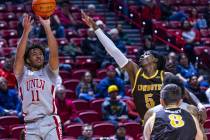 UNLV guard Dedan Thomas Jr. (11) gets off a jump shot past Wyoming Cowboys guard Obi Agbim (5) ...