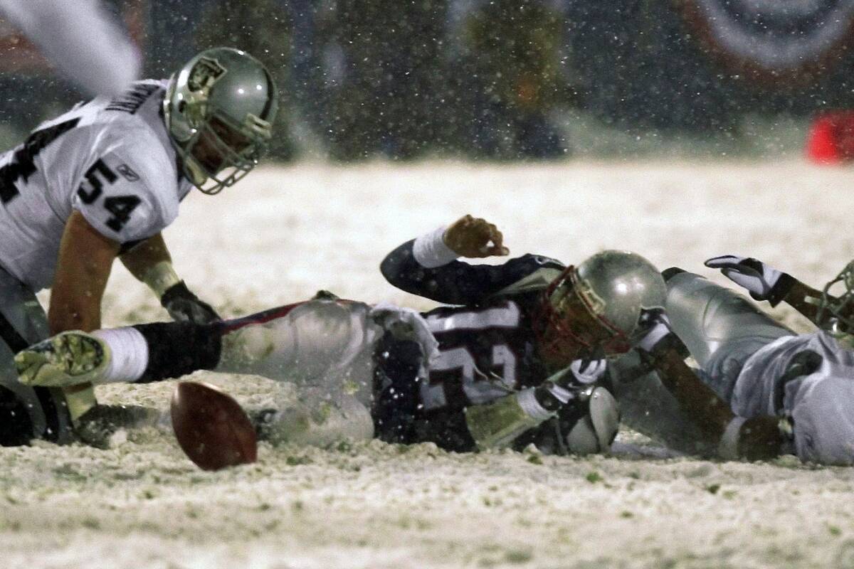 New England Patriots quarterback Tom Brady (12) loses the ball after being brought down by the ...