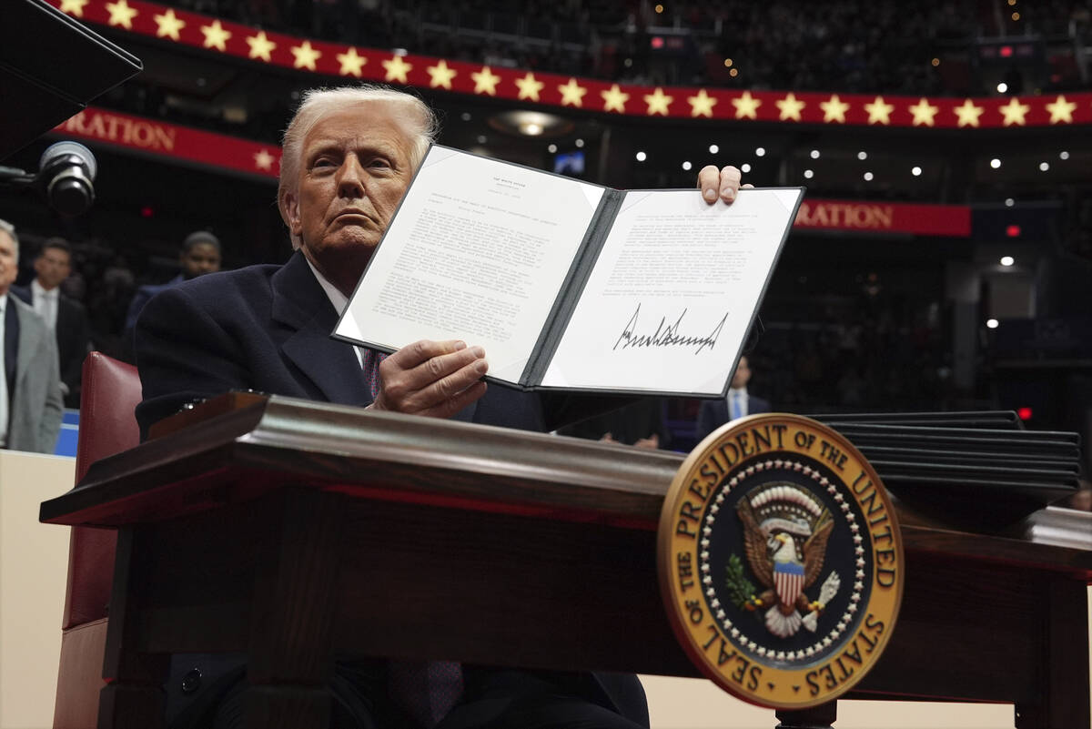 President Donald Trump signs an executive order as he attends an indoor Presidential Inaugurati ...