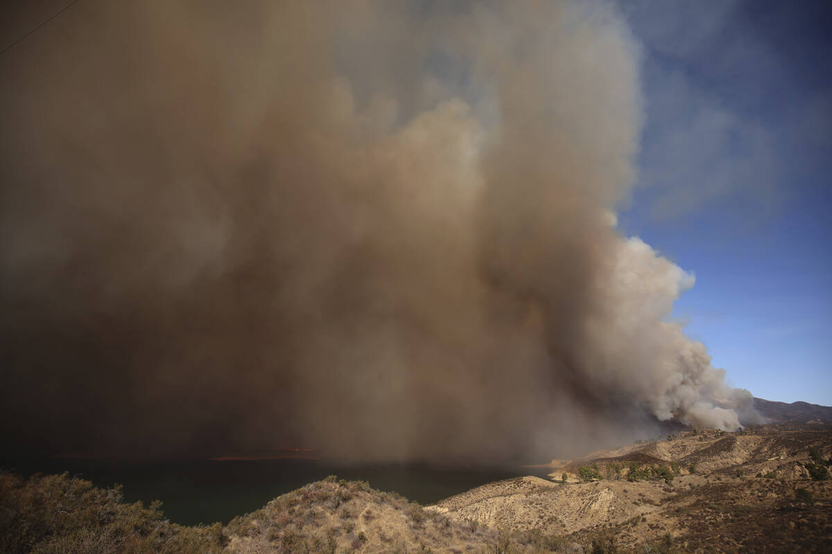 Plumes of smoke caused by the Hughes Fire rise over Lake Castaic, Calif., Wednesday, Jan. 22, 2 ...