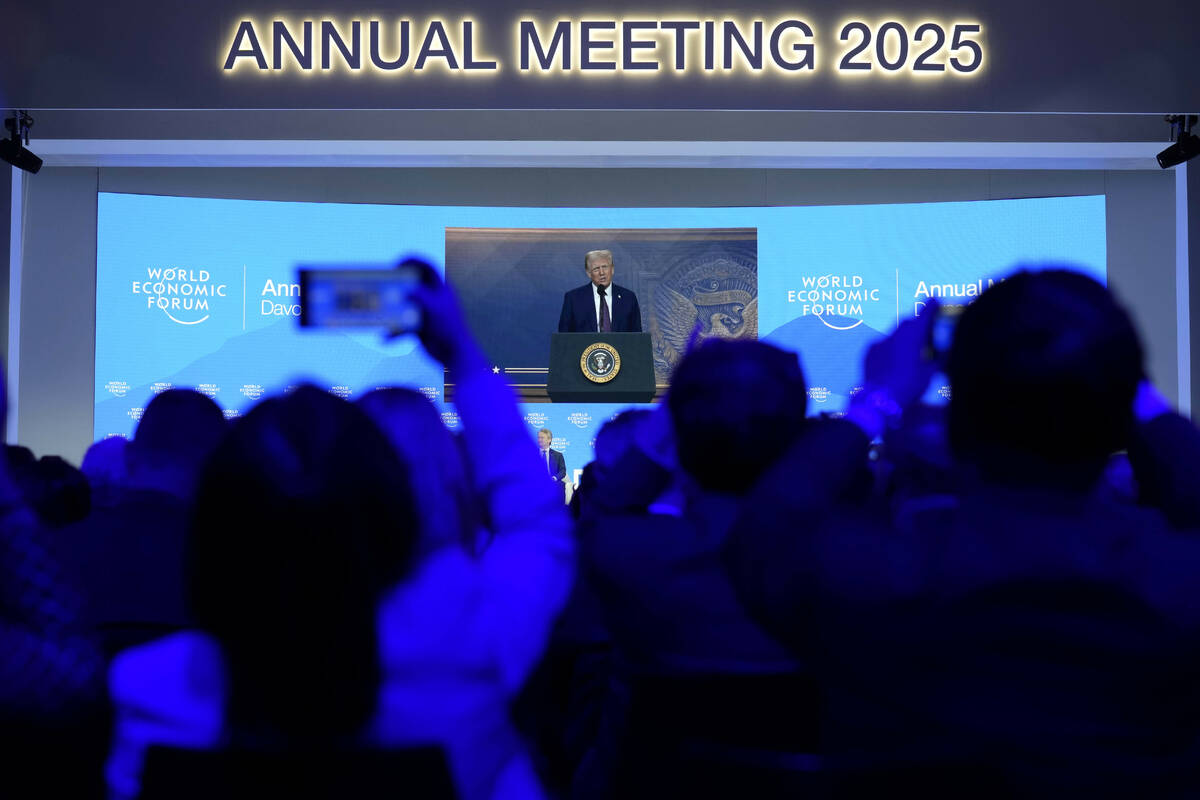 People follow a virtual speech of U.S. president Donald Trump at the Annual Meeting of World Ec ...