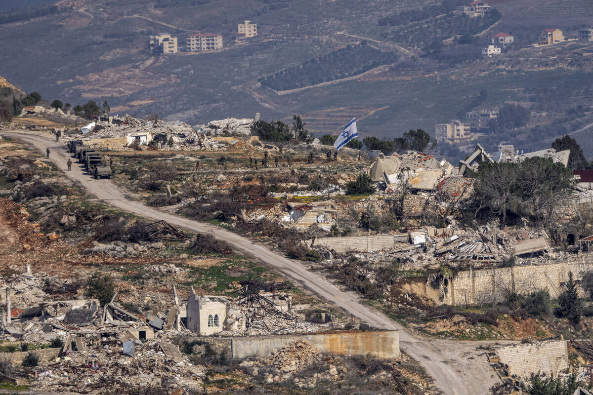 Israeli soldiers stand next to an Israeli flag inside a village in southern Lebanon, as seen fo ...