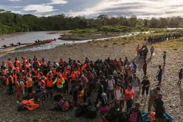 FILE - Migrants line up to board boats to continue their journey north hoping to reach the Unit ...