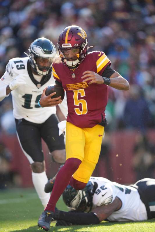 Washington Commanders quarterback Jayden Daniels (5) scrambles with the ball during an NFL foot ...