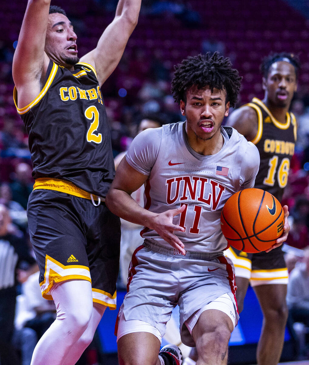 UNLV guard Dedan Thomas Jr. (11) looks to pass against Wyoming Cowboys guard Kobe Newton (2) du ...