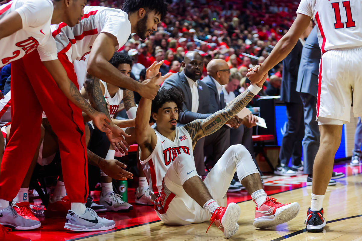 Rebels guard Brooklyn Hicks (13) gets help getting up from his teammates during an NCAA basketb ...