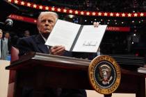 President Donald Trump signs an executive order as he attends an indoor Presidential Inaugurati ...