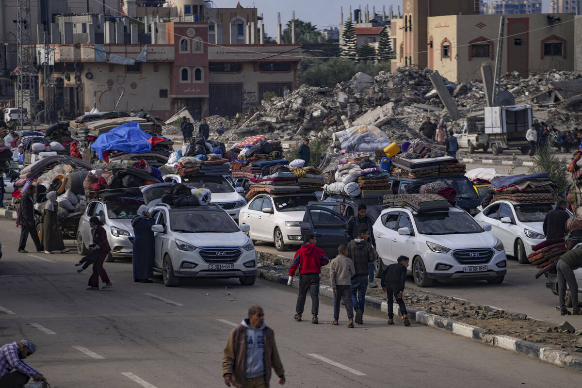 Displaced Palestinians with their belongings gather near a roadblock on Salah al-Din Street, as ...