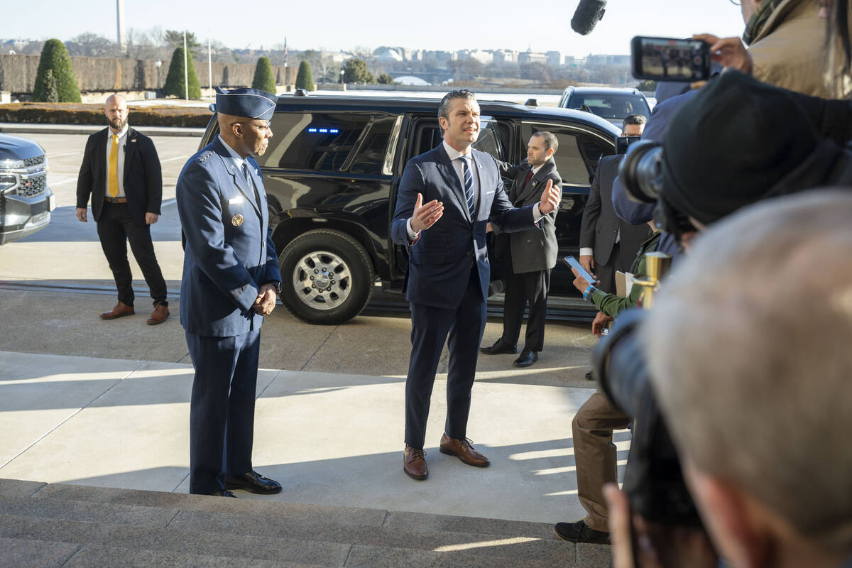 Defense Secretary Pete Hegseth, center right, talks to members of the press after arriving at t ...