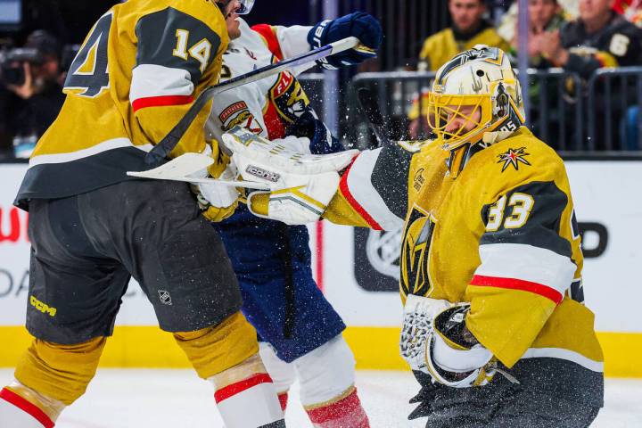 Golden Knights goaltender Adin Hill (33) pushes off teammate Nicolas Hague (14) as he gets clos ...