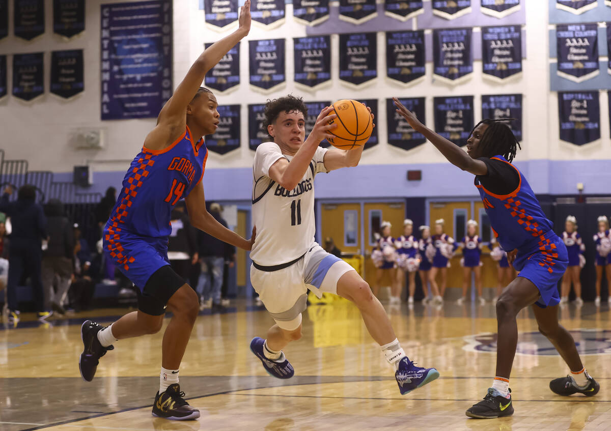 Centennial's Jaxon Price (11) drives to the basket between Bishop Gorman's Kameron Cooper (14) ...