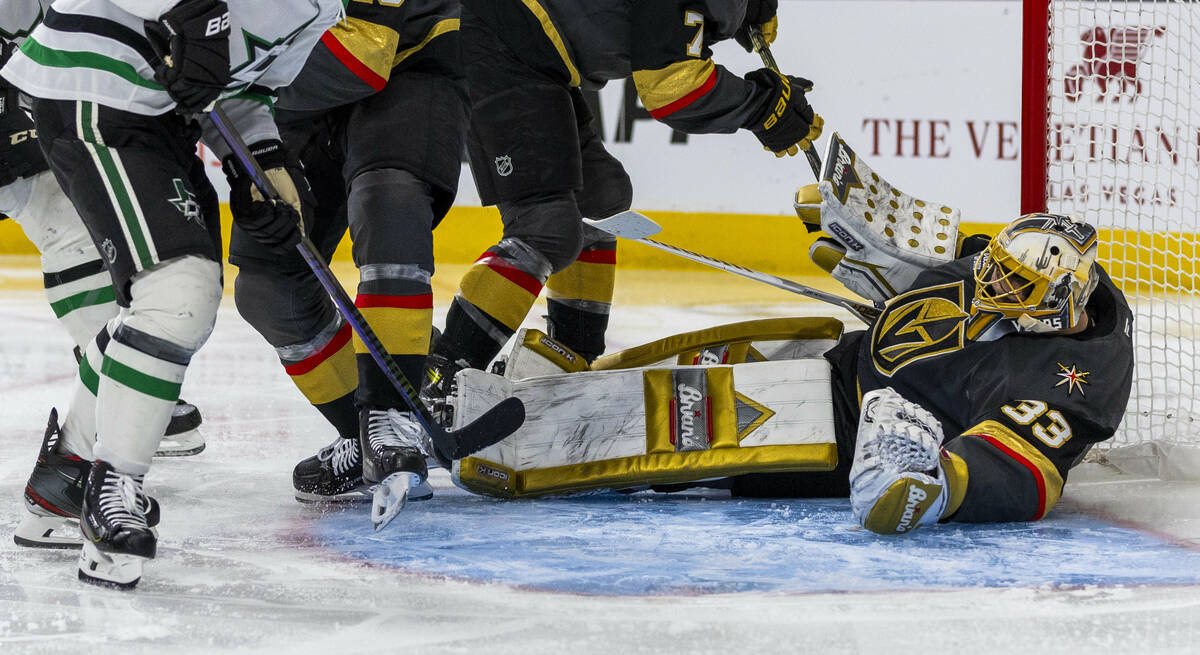 Golden Knights goaltender Adin Hill (33) loses his helmet as he goes to the ice to save a goal ...