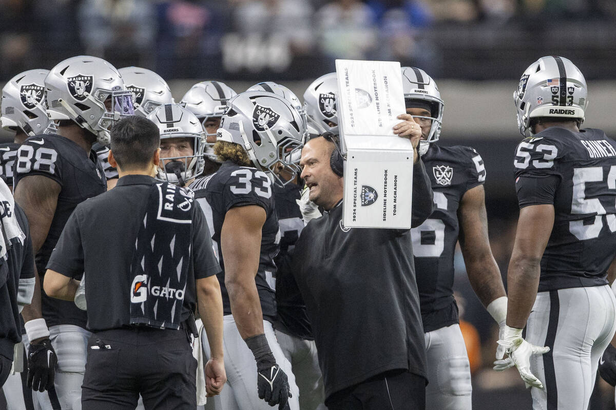 Raiders special teams coach Tom McMahon holds up his sideline notebook as he instructs the spec ...