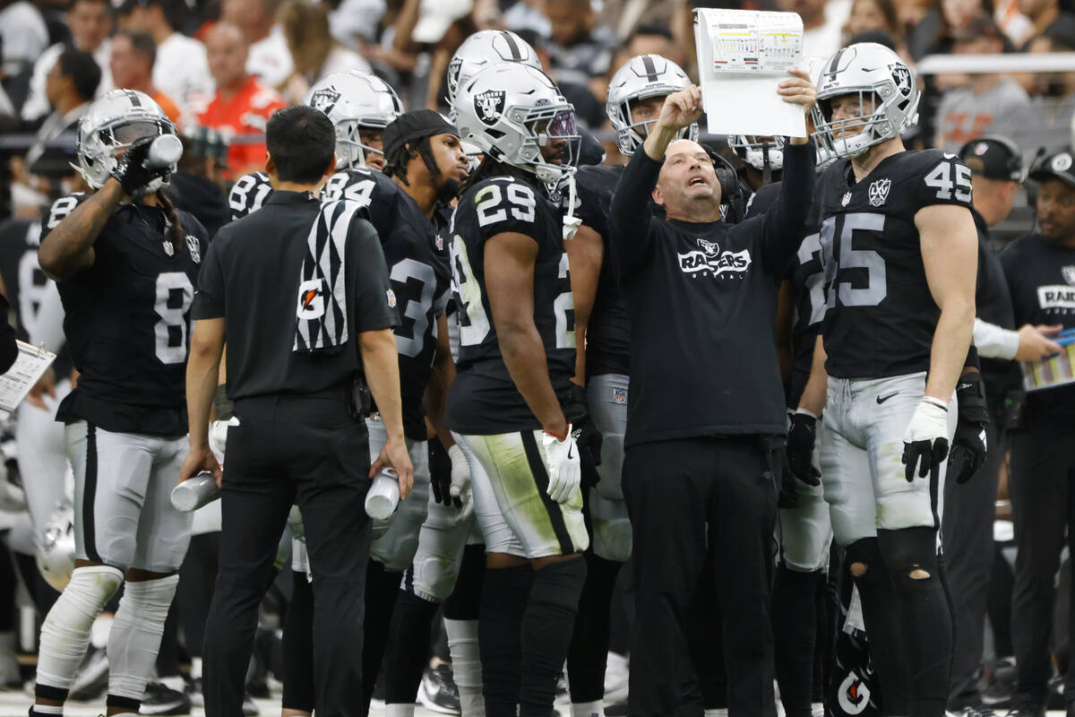 Raiders special teams coordinator Tom McMahon reviews his playbook with players from the sideli ...